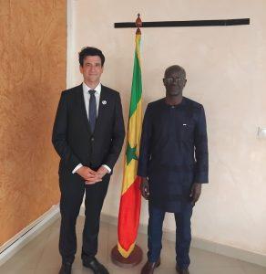 Le secrétaire d'état à la culture du Sénégal et le Directeur général de France Volontaires posent à côté du drapeau du Sénégal